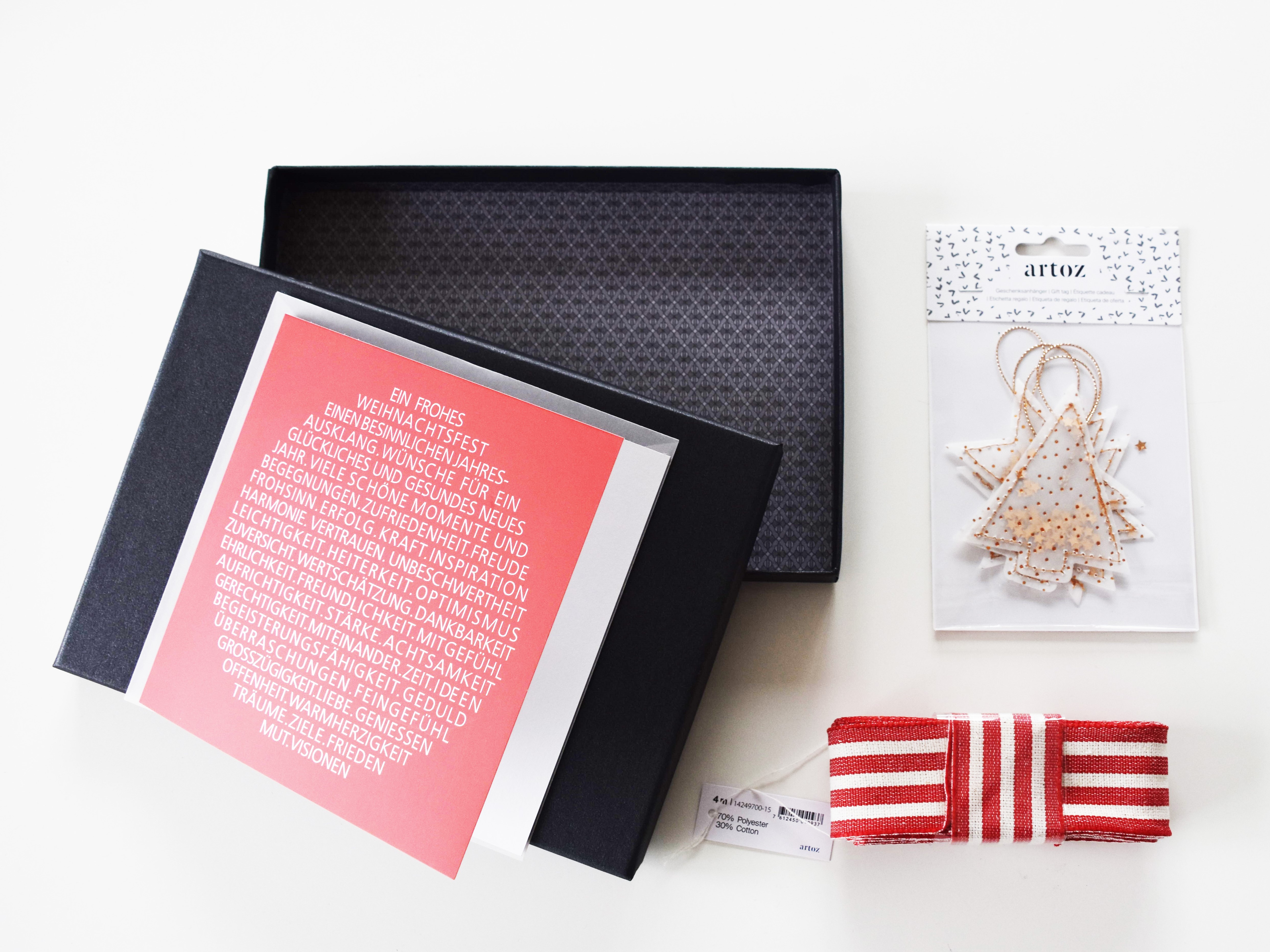 pure-box-black-glow-schwarz-rote-weihnachtskarte-design-kugel_rot-weisses-geschenkband-und-anh-nger-von-artoz